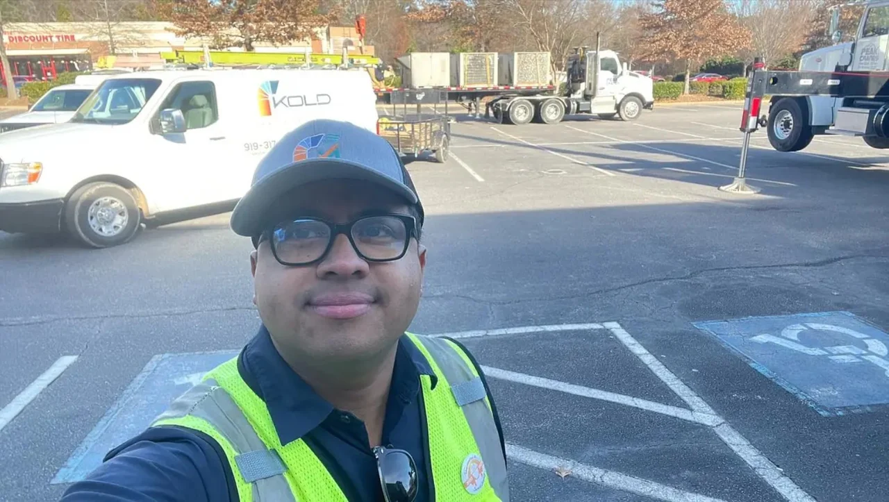 A person in branded field clothing with a KOLD van and equipment logistics behind them.